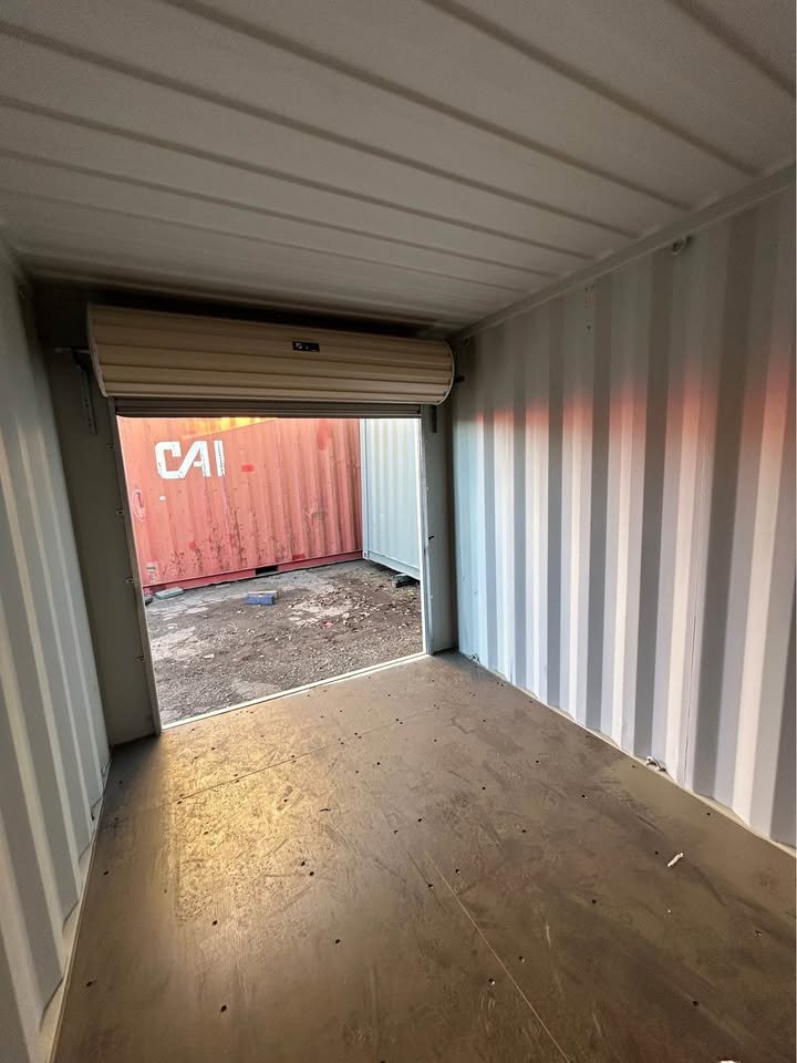 Inside a 10ft roller door container looking out through the open roller shutter, with plywood floor